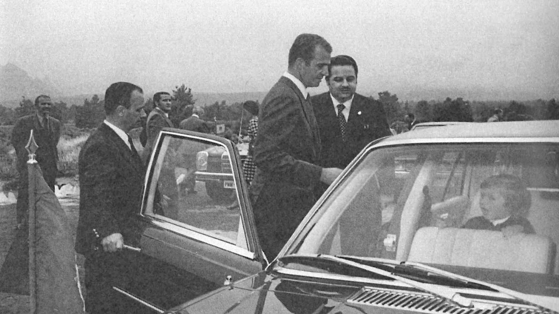 Imagen del Príncipe Juan Carlos de Borbón en el Parador Nacional del Teide (1973). En el interior del coche, su hijo Felipe de Borbón. Al lado de la puerta del automóvil, el conductor del presidente del cabildo de Tenerife, Sr. Puerta